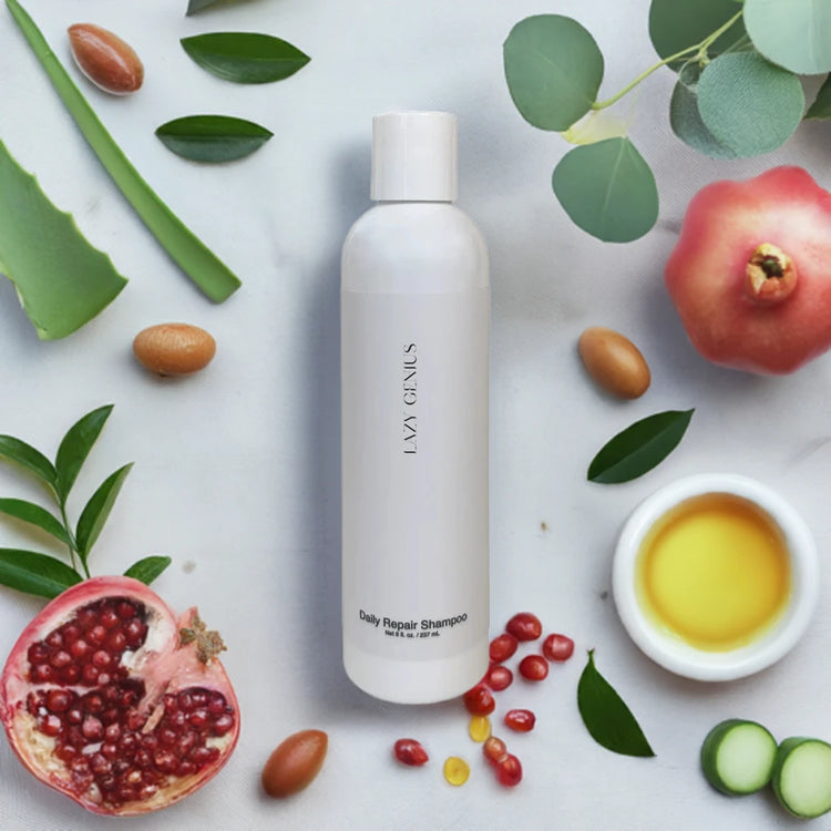 Daily Repair Shampoo surrounded by natural ingredients like aloe vera, pomegranate, and olive oil.