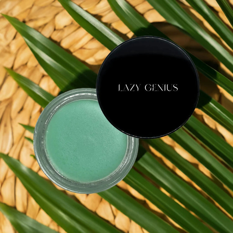 Lazy Genius mint green lip balm in a jar, surrounded by tropical leaves.